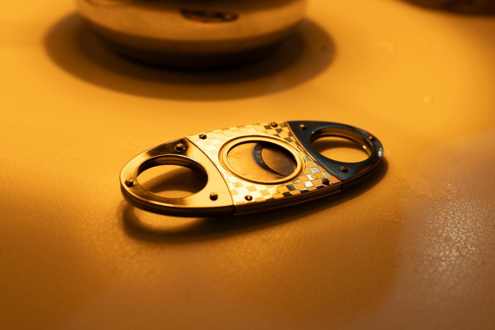 A stainless steel cigar cutter on a table, a key tool for cigar maintenance