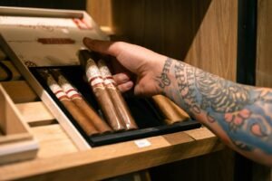 An open wooden humidor holding premium cigars, requiring regular maintenance