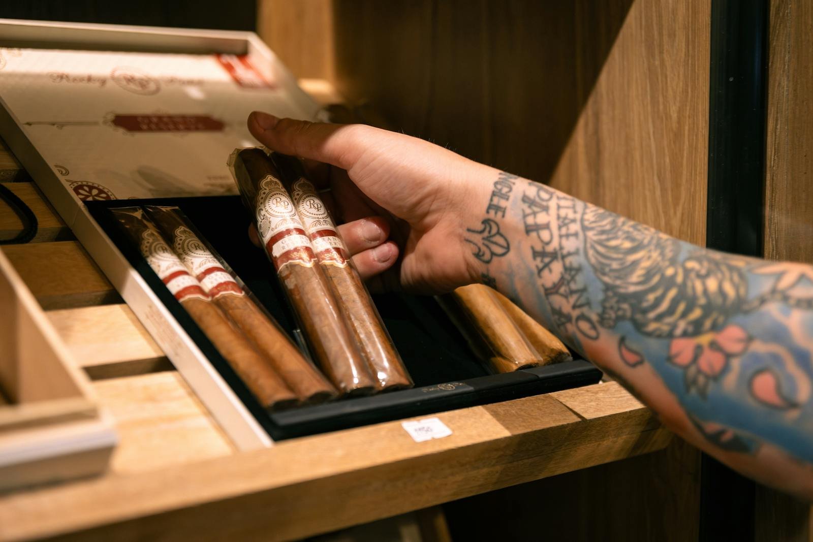 An open wooden humidor holding premium cigars, requiring regular maintenance