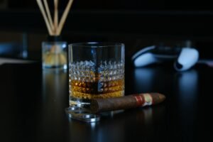 A glass of whisky paired with a premium cigar on a dark tabletop