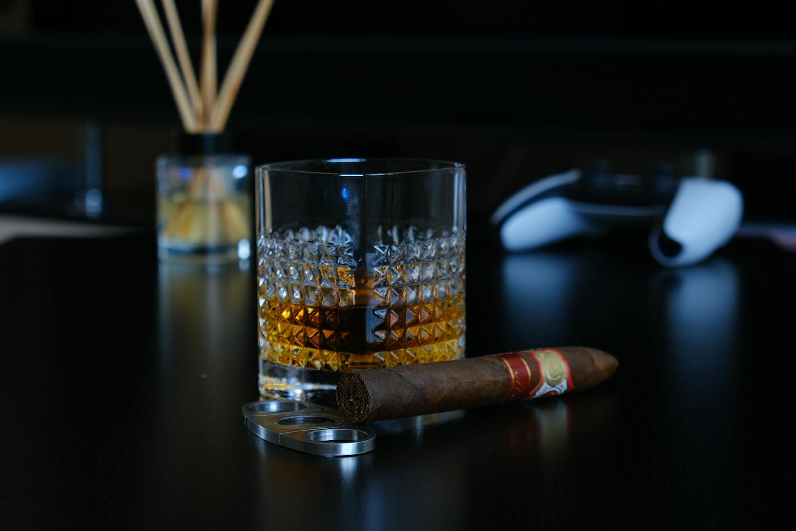 A glass of whisky paired with a premium cigar on a dark tabletop